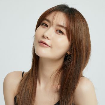 Woman with long brown hair against a plain background