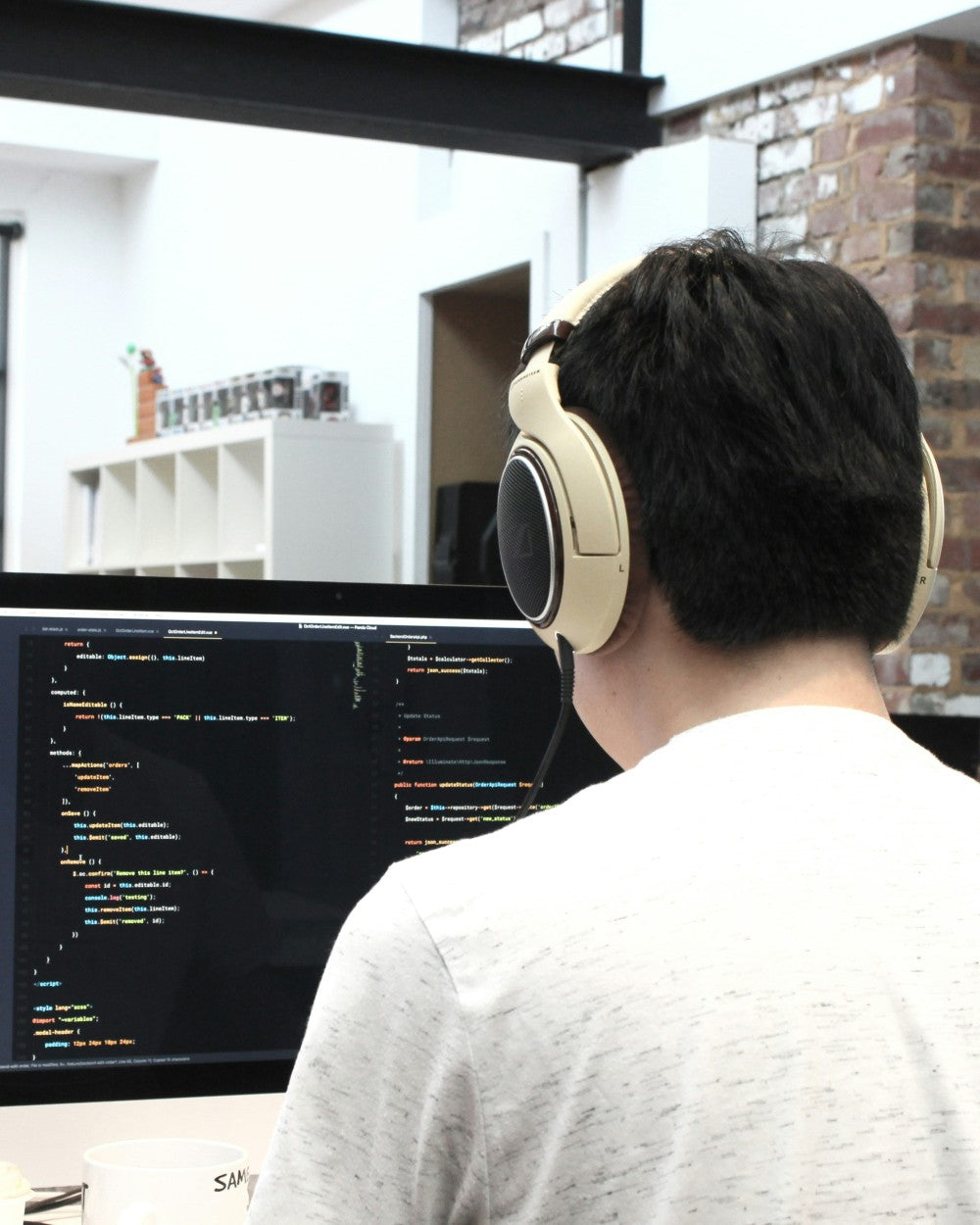 Person wearing headphones working on a computer with code displayed on the screen.